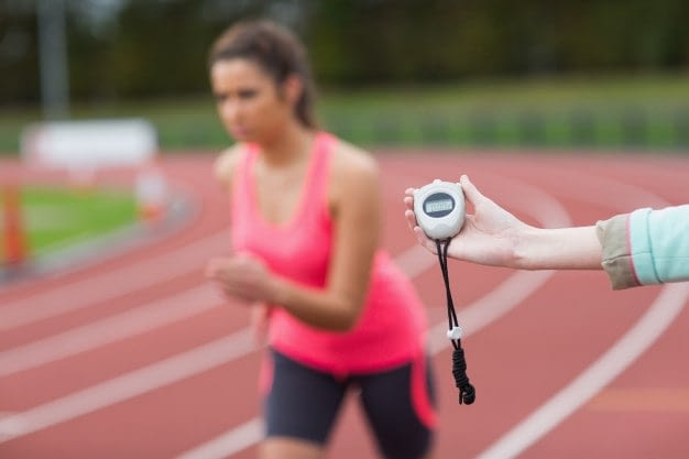 Valoración de la condición físicas del opositor para preparar las pruebas físicas a las oposiciones - mujer corriendo en una pista de atletismo mientras es cronometrada su carrera