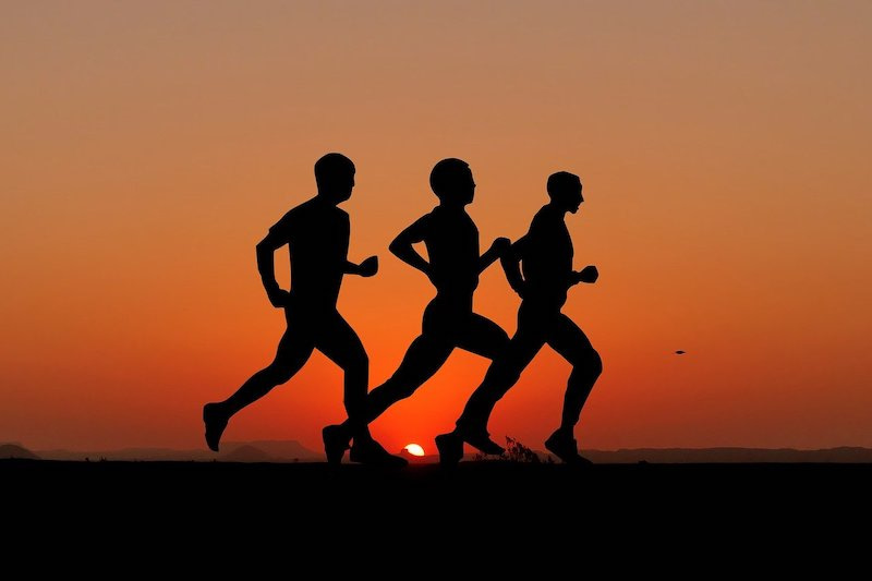 Silueta deportistas corriendo al atardecer - consejos para entrenar y hacer ejercicio fisico en verano