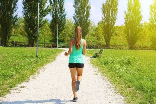 Calentamiento físico general, carrera suave - mujer corriendo por un camino